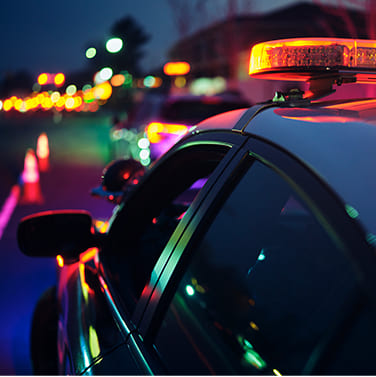 A police car is parked at a sobriety checkpoint